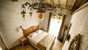 Un dormitorio con una cama de madera, una mesita de noche, un espejo grande y una araña con lámparas colgantes.