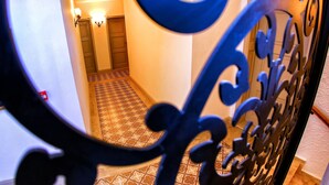 Un pasillo con piso estampado, una puerta al final e iluminación empotrada en las paredes.