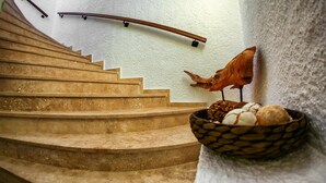 Una escalera con barandilla de madera, un estante de pared con una cesta de huevos y una escultura decorativa de un pájaro.