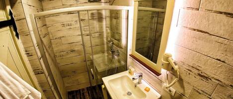 A bathroom with a glass shower enclosure, a sink, and a mirror.