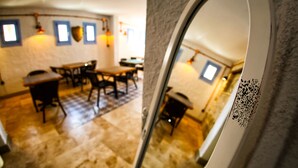 Una habitación con comedor, que incluye mesas y sillas, y vista a través de un vano.
