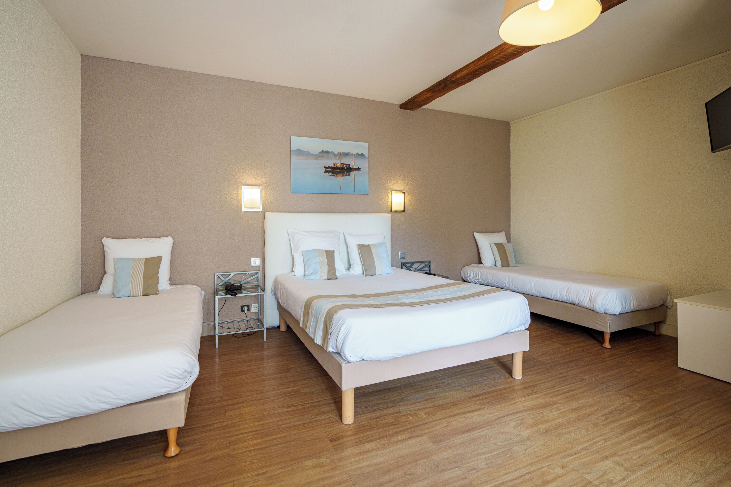 Une chambre avec deux lits simples et un lit plus grand, un plancher en bois et un tableau au mur.