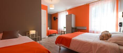 A hotel room with two beds, a desk, a wardrobe, and a television.