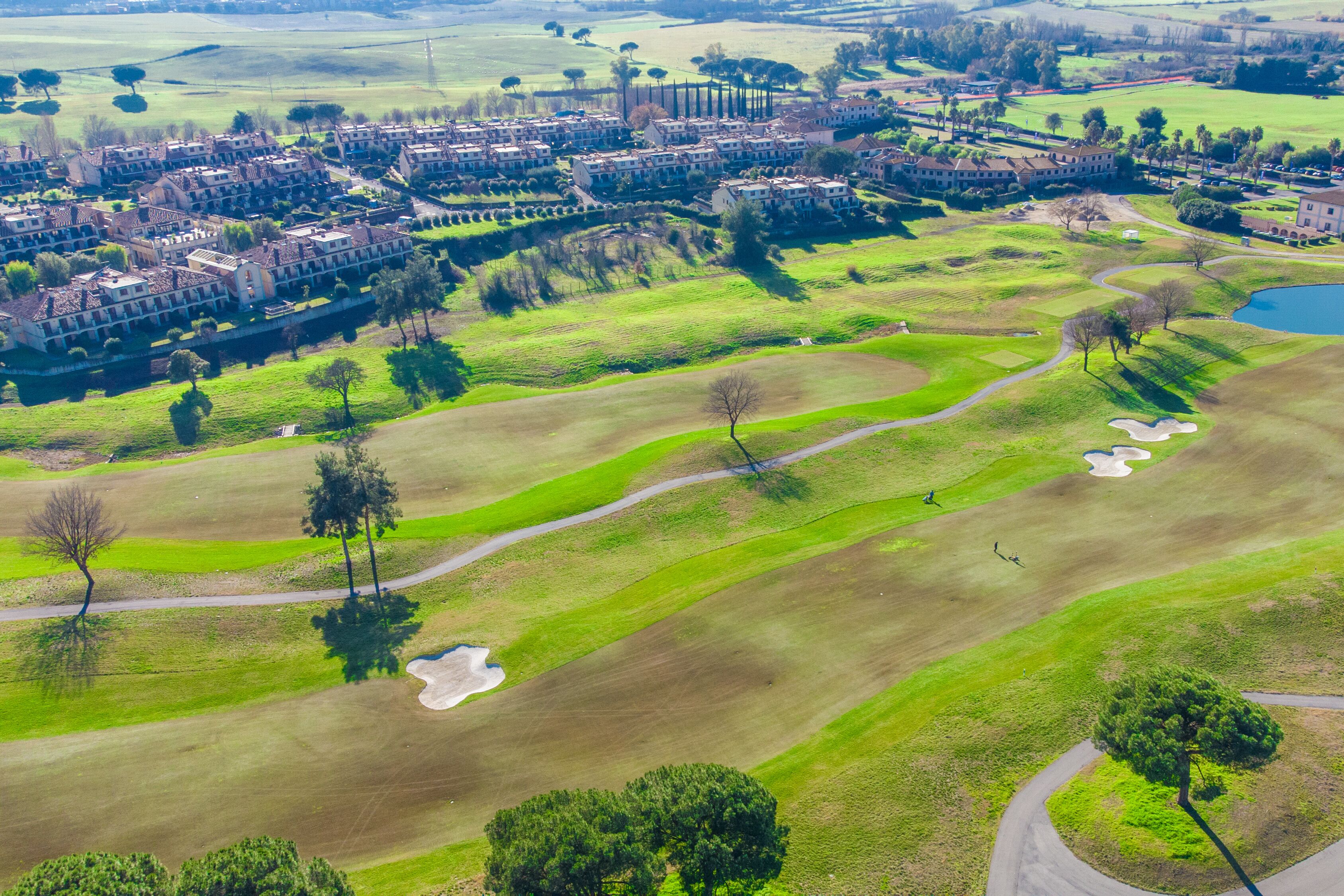 An aerial view of a golf course with a residential area and a large building complex.