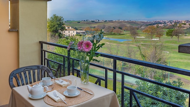 Mesa posta para o chá, com vista para um campo de golfe e edifícios ao longe.
