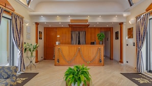 Uma área de recepção de hotel com um balcão de madeira, plantas em vasos e design de interiores moderno.