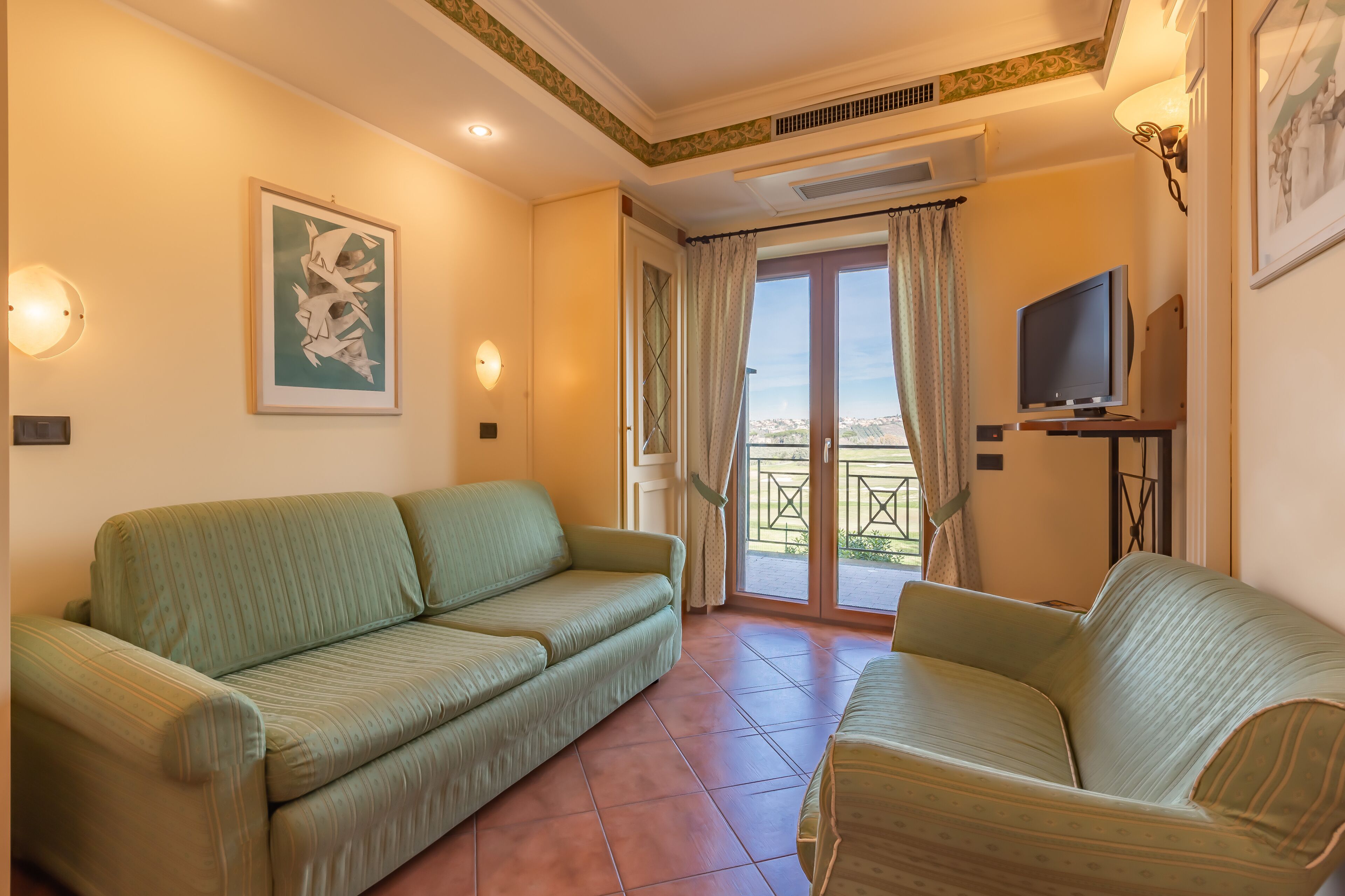 Une pièce avec deux canapés, un téléviseur et un balcon avec des rideaux.