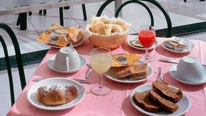 Una mesa de desayuno con diversos alimentos, como pasteles, pan y un vaso de jugo.