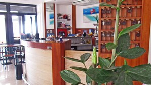 Un vestíbulo de hotel con mostrador de recepción, zona de estar y una pared decorada con una planta.