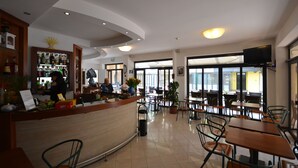 Un restaurante con barra, sillas, mesas y un televisor montado en la pared.