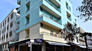 Un hotel de varios pisos con fachada azul, zona de estar al aire libre y un letrero que dice 'Hotel La Plage'.