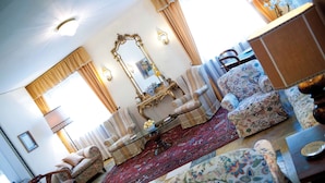 Un salón tradicional con un espejo grande y ornamentado, sofás estampados y una alfombra roja.