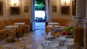 Un comedor con mesas, bancos y un bufé con frutas y cereales.