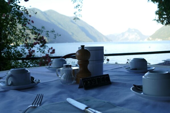 Una mesa preparada para el té con vistas a las montañas y un lago.
