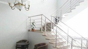 A staircase with metal railings, two chairs, a small table, and a potted plant. - Royal Petrol Hotel Taldykorgan (Taldykorgan)