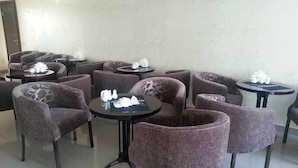 A seating area with round tables and cushioned chairs, arranged in a semi-circle. - Royal Petrol Hotel Taldykorgan (Taldykorgan)
