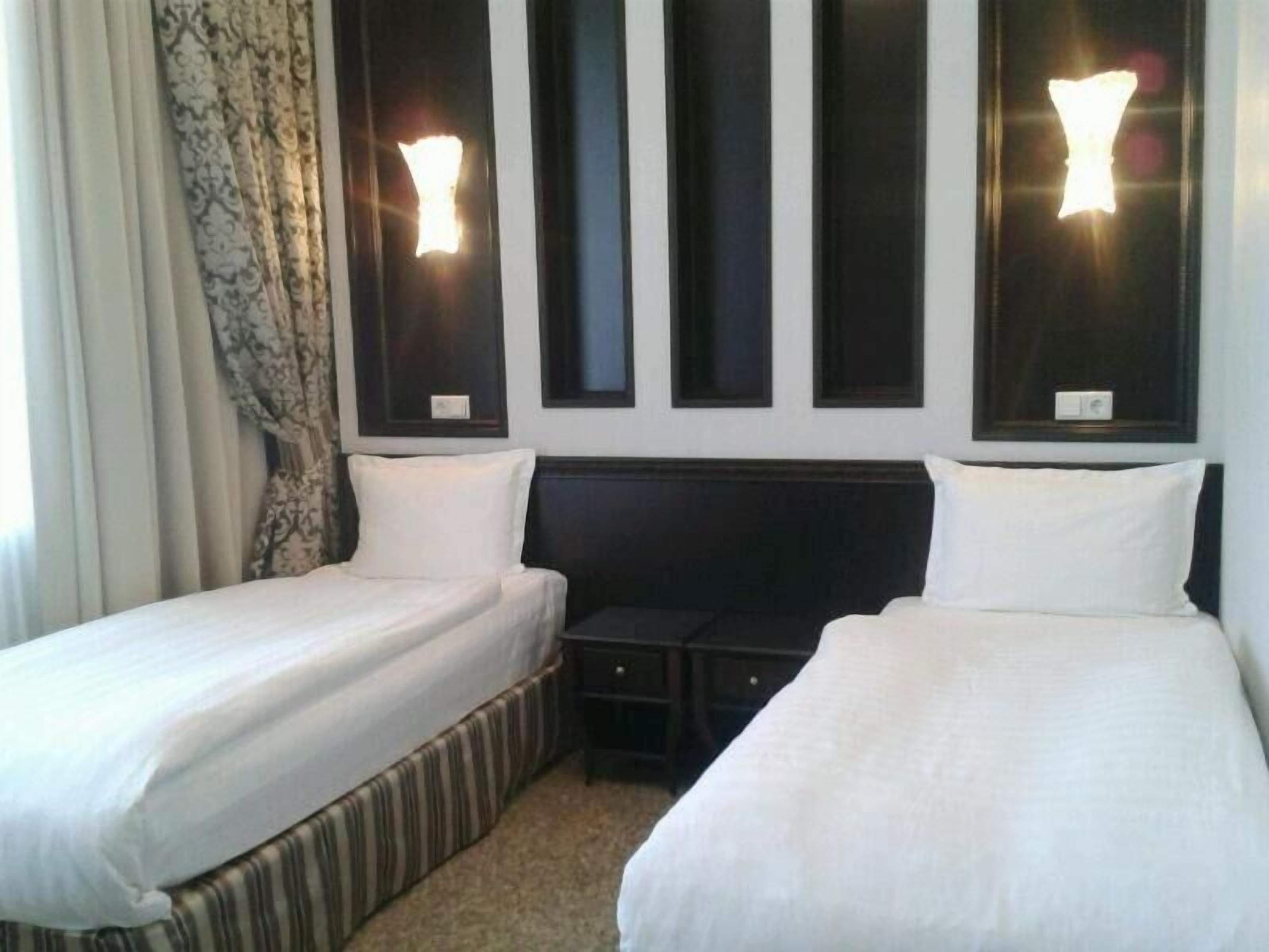 Una habitación de hotel con dos camas individuales, una mesita y un cabecero oscuro.