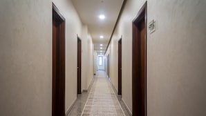 A long, narrow hallway with wooden doors on both sides, leading to a bright room at the end. - Royal Petrol Hotel Taldykorgan (Taldykorgan)