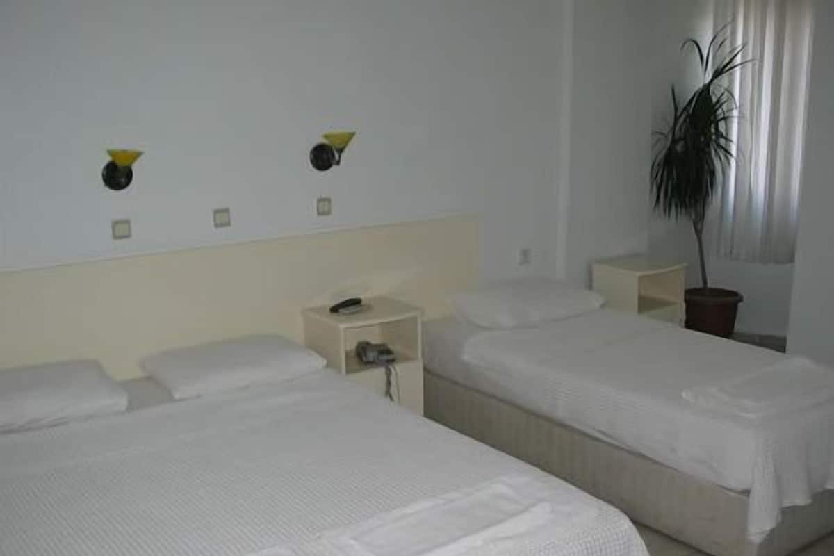 A hotel room with two beds, a nightstand, a potted plant, and a wall-mounted light fixture.