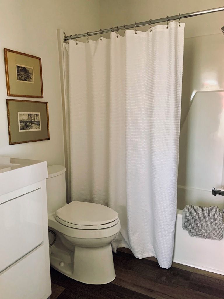 Une salle de bain équipée de toilettes, d’un rideau de douche et d’un porte-serviettes.