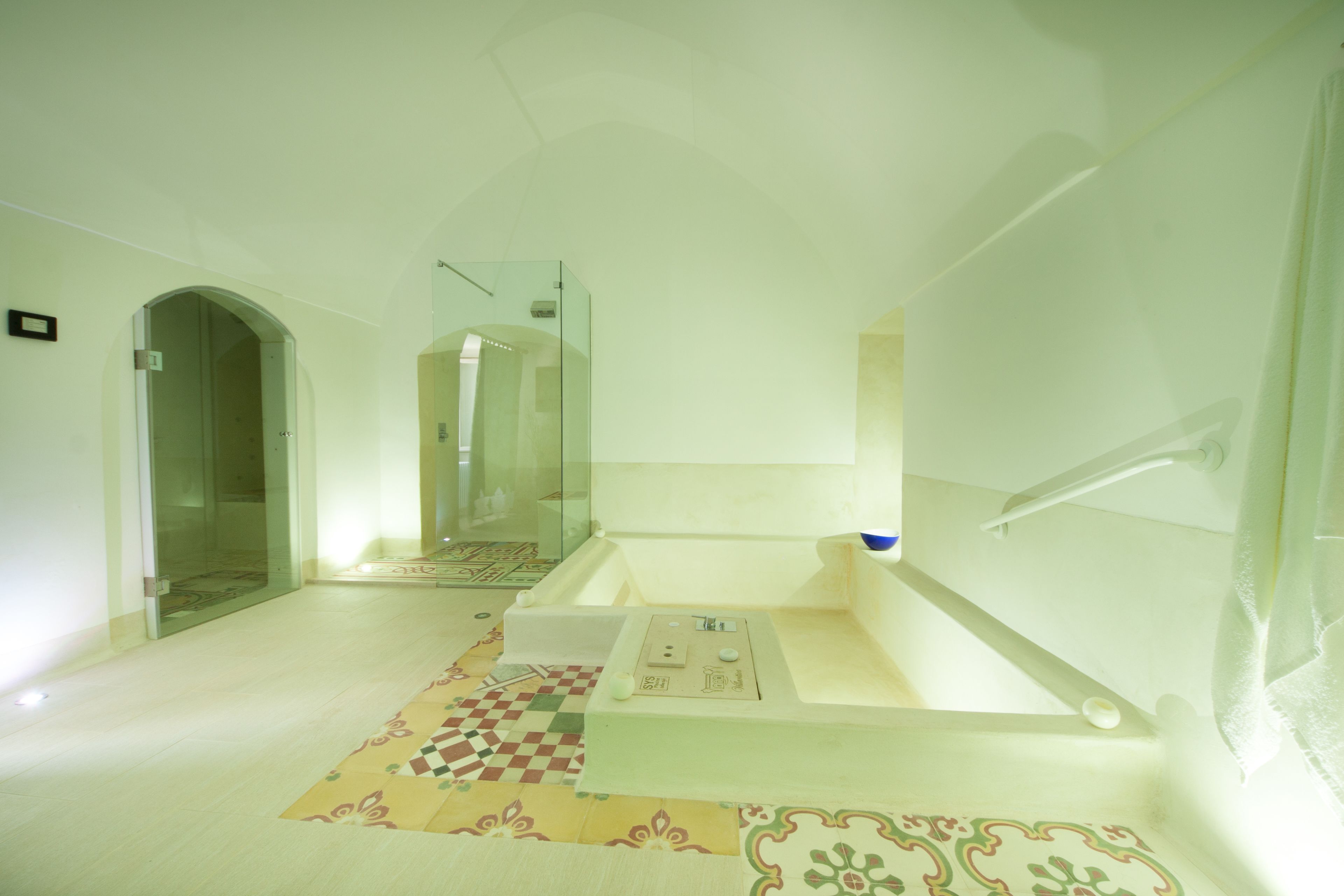 Ein modernes Badezimmer mit einer Duschkabine aus Glas, einer Badewanne und einem gemusterten Boden.