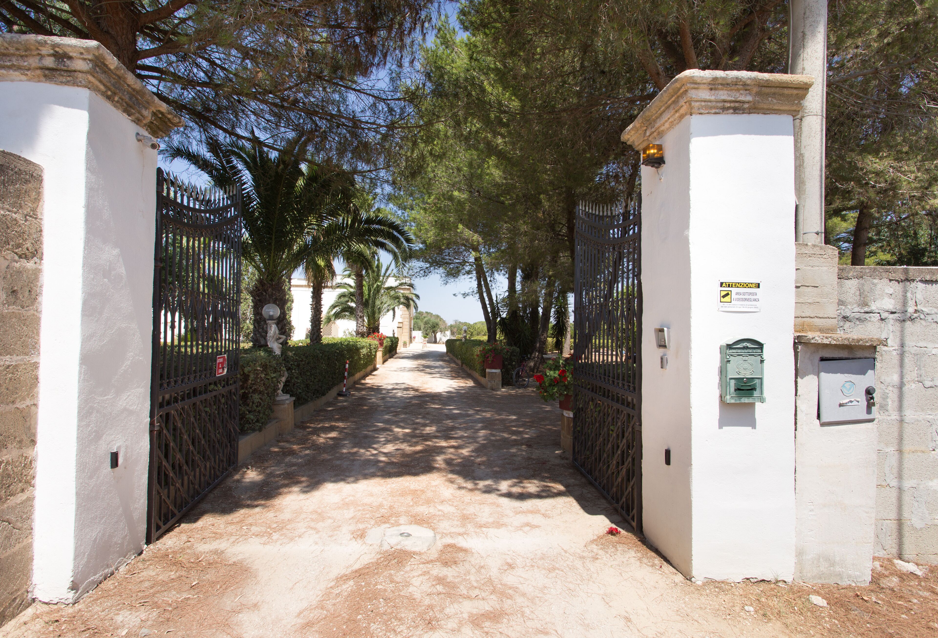 Une entrée fermée par un portail, avec un chemin menant à un bâtiment.