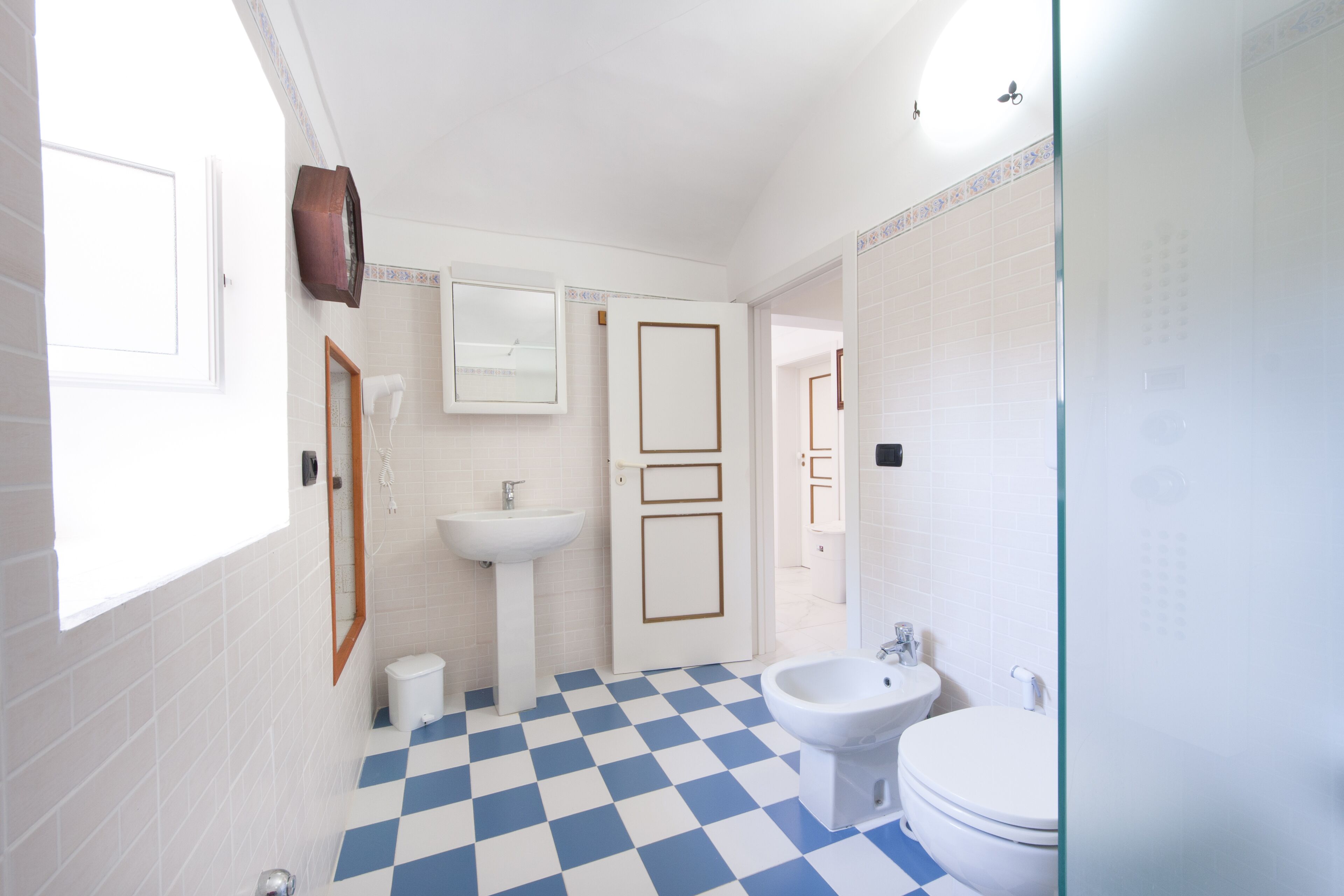 A bathroom with a checkered floor, a sink, a bidet, and a toilet.
