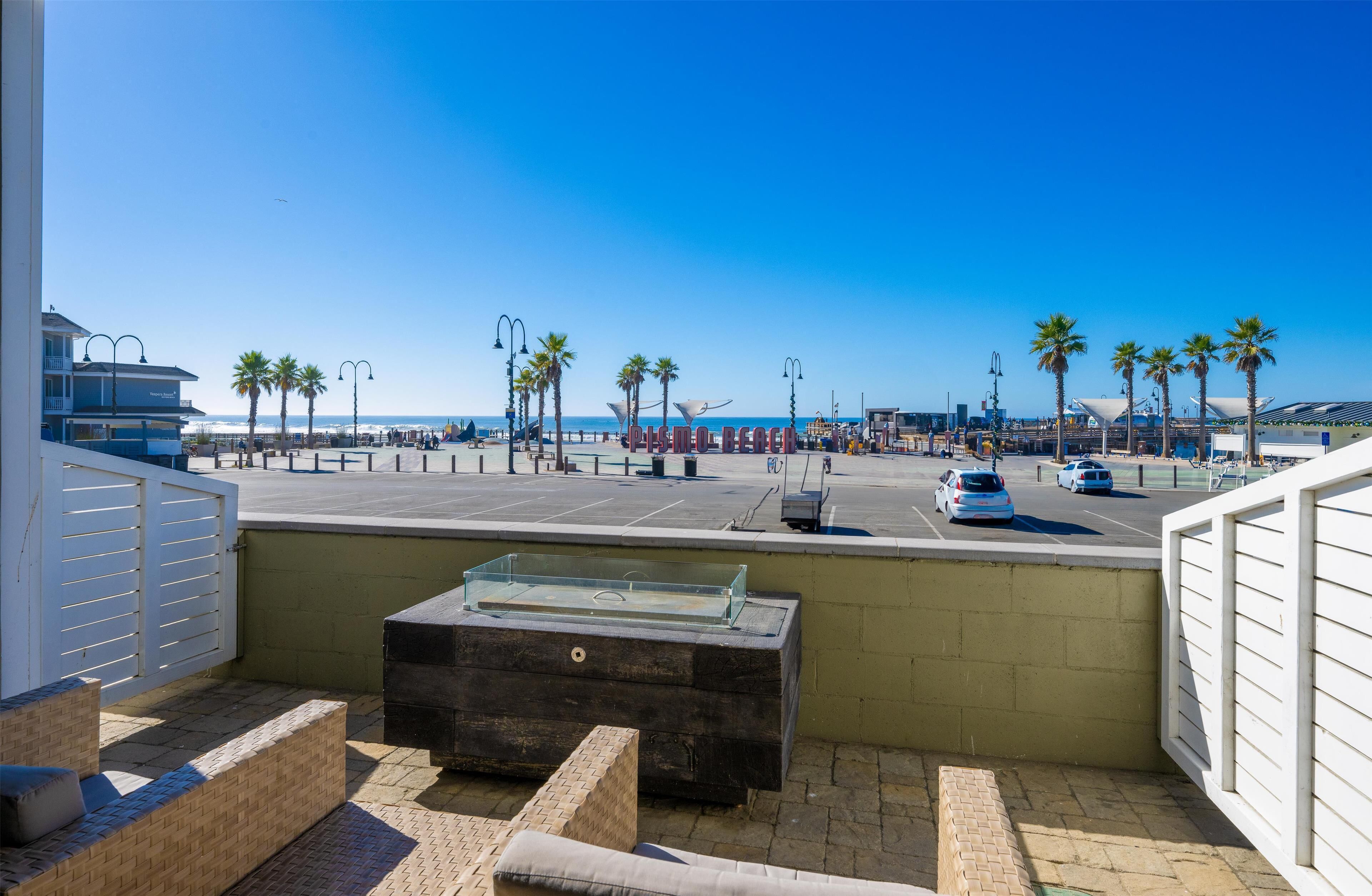 Un balcon avec vue sur la plage, les palmiers et un espace de stationnement.