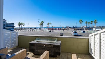 Un balcon avec vue sur la plage, les palmiers et un espace de stationnement.