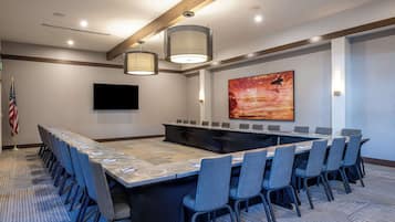 A conference room with a long table, chairs, a flag, and a painting on the wall.