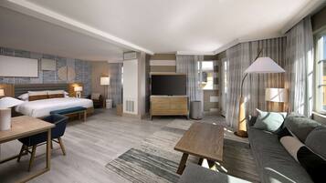 A modern hotel room with a bed, desk, sofa, and TV.