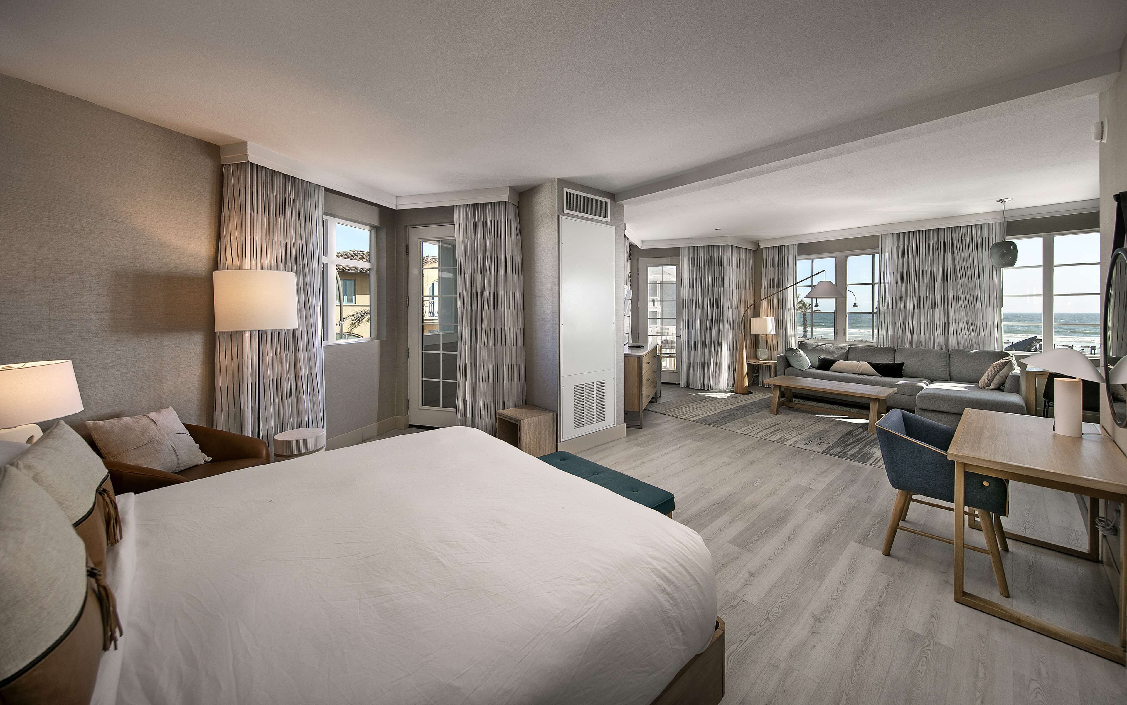 A hotel room with a large bed, a sofa, a desk, and a view of the ocean.