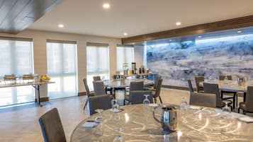 Un comedor moderno con mesas redondas, sillas y un ventanal con vistas a un paisaje montañoso.