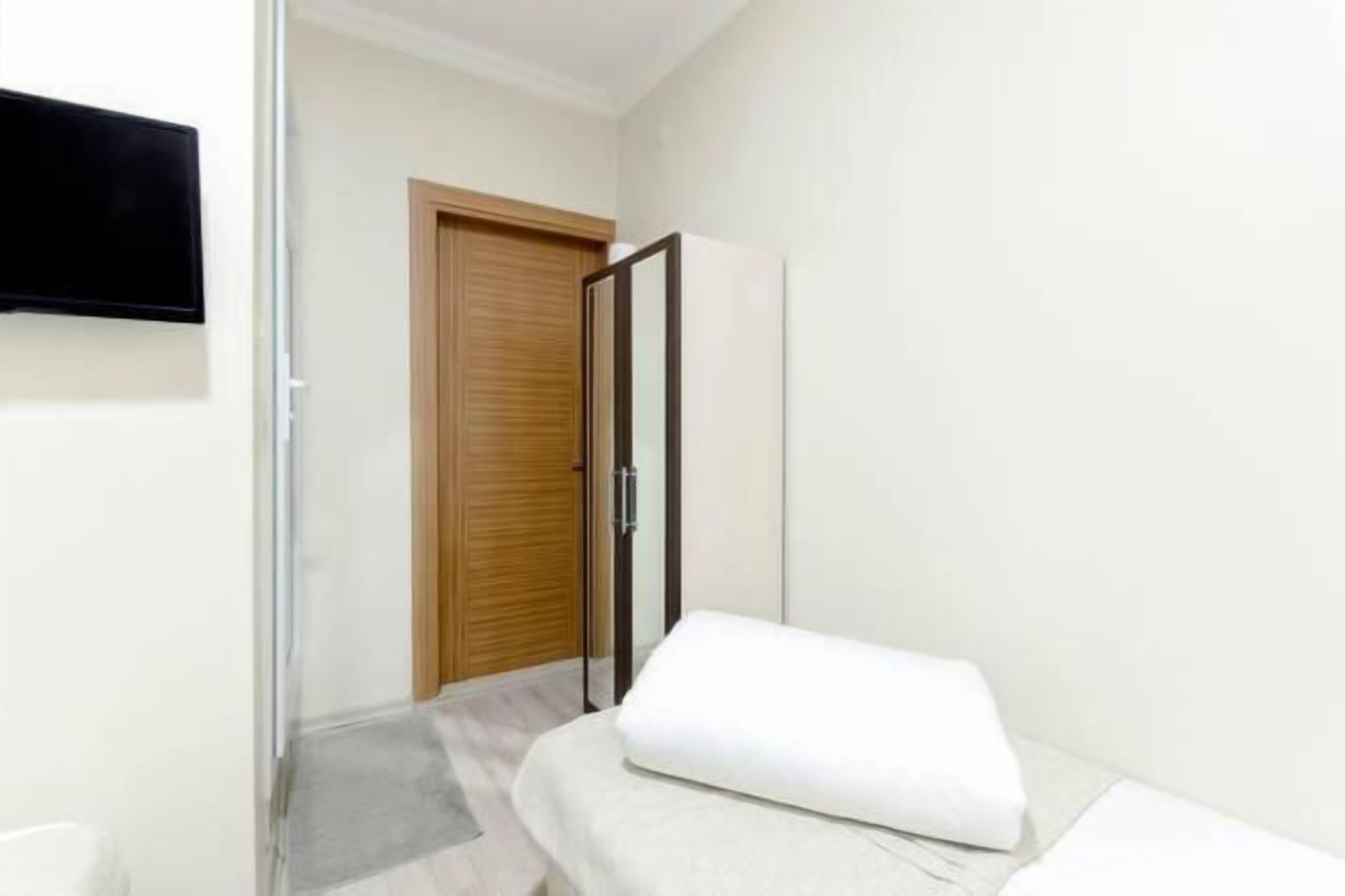 A modern hotel room with a bed, a wardrobe, and a television mounted on the wall.