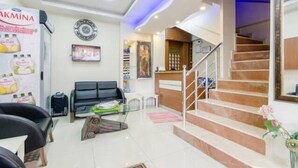 A hotel lobby with a reception desk, a staircase, and a seating area with a sofa and chairs. - Agora Park Hotel (Izmir)
