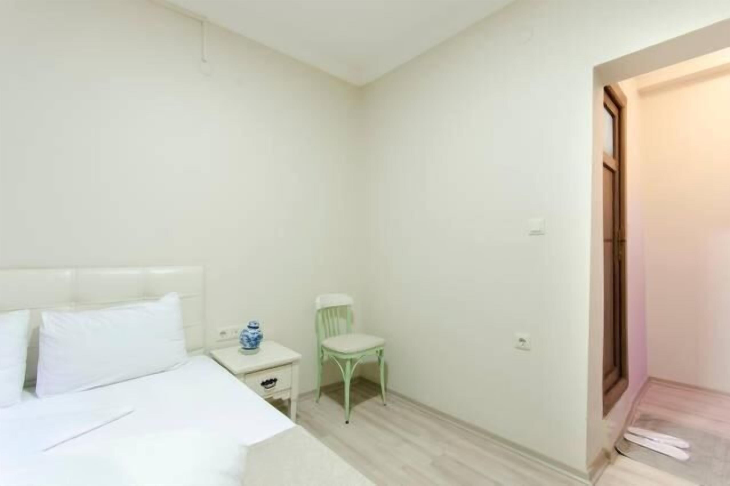 Una camera da letto con un letto, un comodino, una sedia e una porta.
