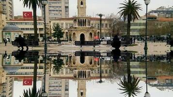 Una plaza con una fuente central, una torre de reloj y palmeras.