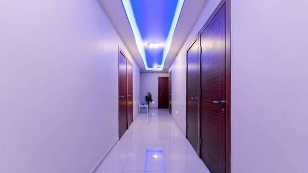 A modern hallway with a blue-lit ceiling, polished floors, and wooden doors. - Agora Park Hotel (Izmir)