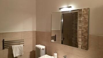 Een moderne badkamer met een grote spiegel, een handdoekhouder, een radiator en een wastafel.