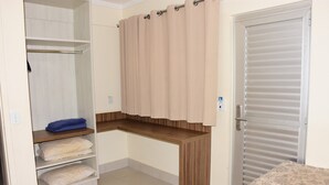 Un dormitorio con cama, armario, escritorio y baño.