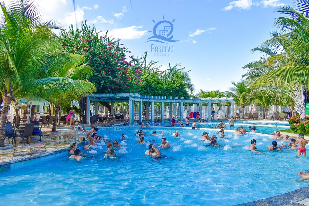A pool area with multiple swimming pools, palm trees, and a covered seating area.