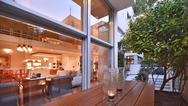 A modern interior with a wooden table, glass vases, and a cozy seating area. - Villa Amaryllis (Athens)