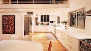 A modern kitchen with white cabinetry, stainless steel appliances, and a wooden floor. - Villa Amaryllis (Athens)