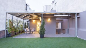 A covered patio area with artificial grass, potted plants, and a seating arrangement. - Acropolis Stay (Athens)