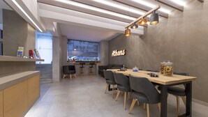 A modern dining area with a long wooden table, black chairs, and a neon sign on the wall. - Acropolis Stay (Athens)