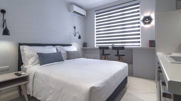Une chambre moderne avec un lit, des tables de chevet, un bureau et une fenêtre avec des stores.