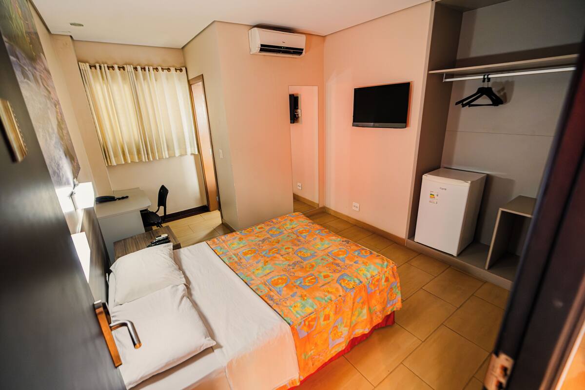 Une chambre d’hôtel équipée d’un lit, d’un bureau, d’une chaise, d’une télévision, d’un climatiseur et d’une armoire.