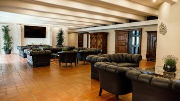 A spacious living area with leather sofas and a large flat-screen TV mounted on a brick wall.