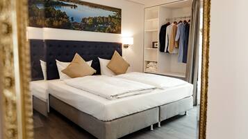 A modern hotel room with a large bed, a wardrobe, and a painting of a landscape.
