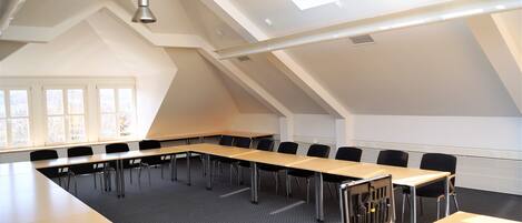 A conference room with a long table, chairs, and a ceiling with skylights.